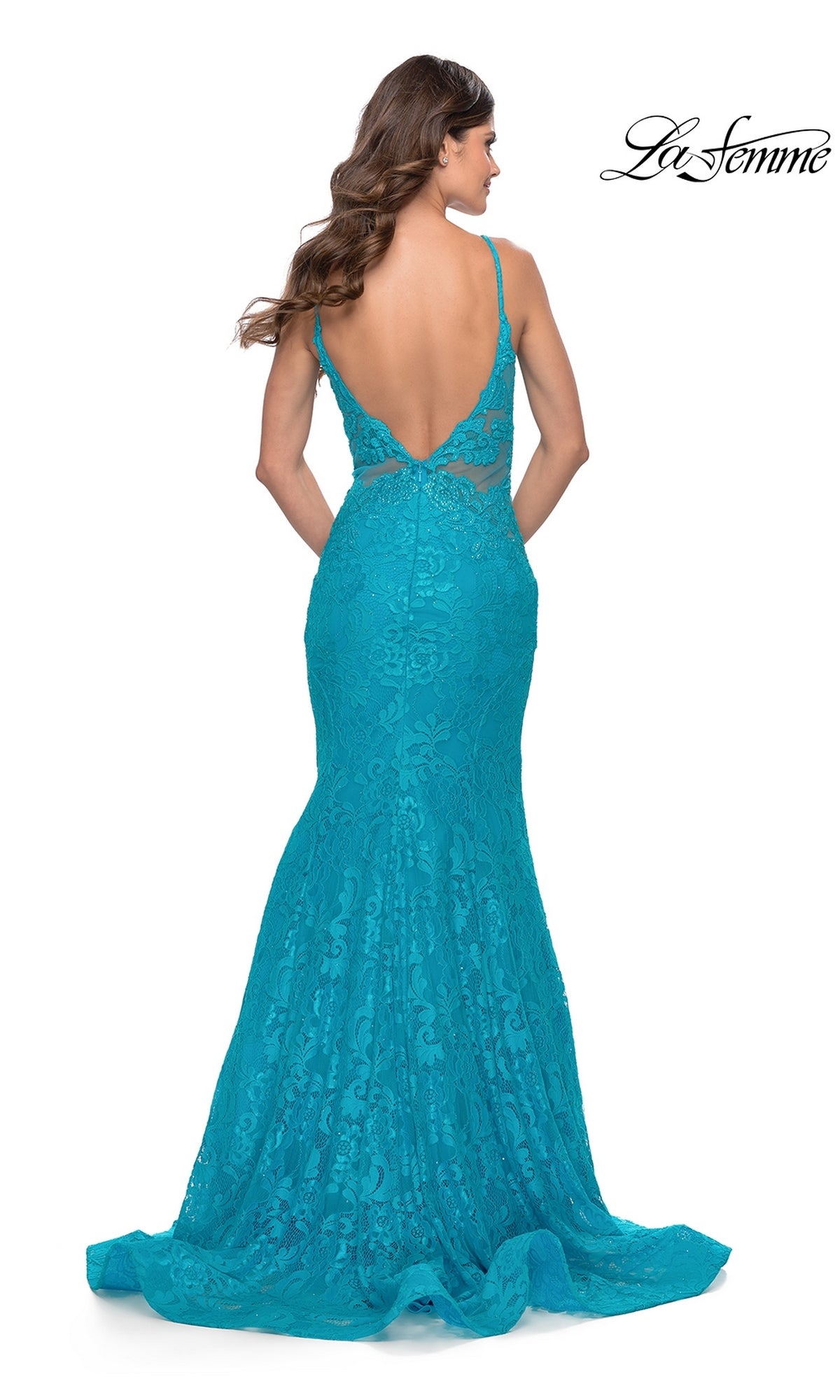 A woman in the La Femme 31512, a long teal lace mermaid prom dress with thin straps and a deep V-back, poses with her back to the camera. The La Femme logo appears in the upper right corner.